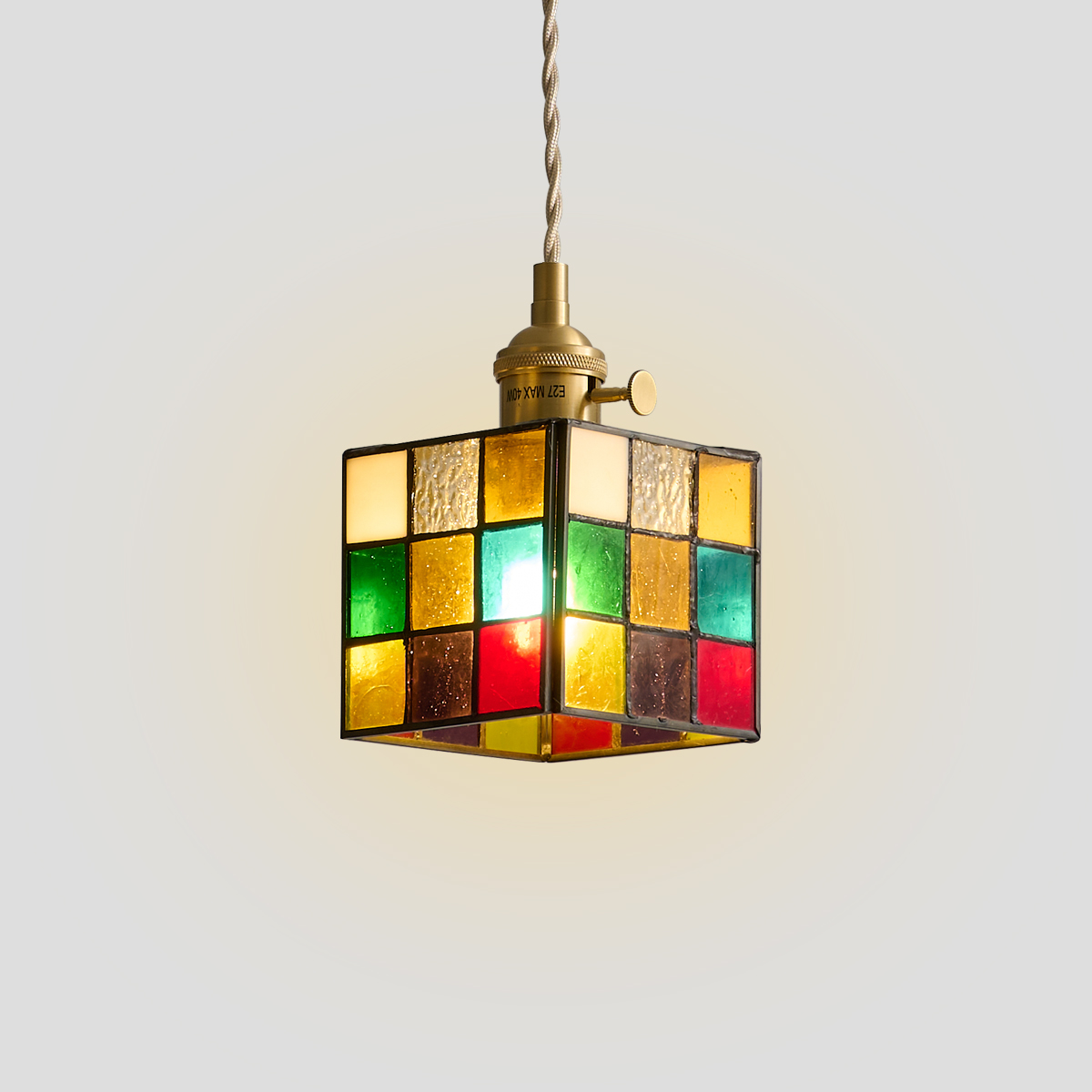 Vintage Stained Glass Cube Pendant Light 1 Vintage style multi-colored glass hanging lamp with brass frame hanging in a cozy living room reading corner
