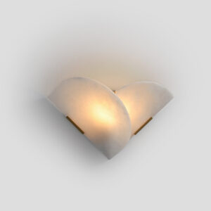 Modern natural alabaster wall sconce with brushed brass accents illuminated on a white wall.