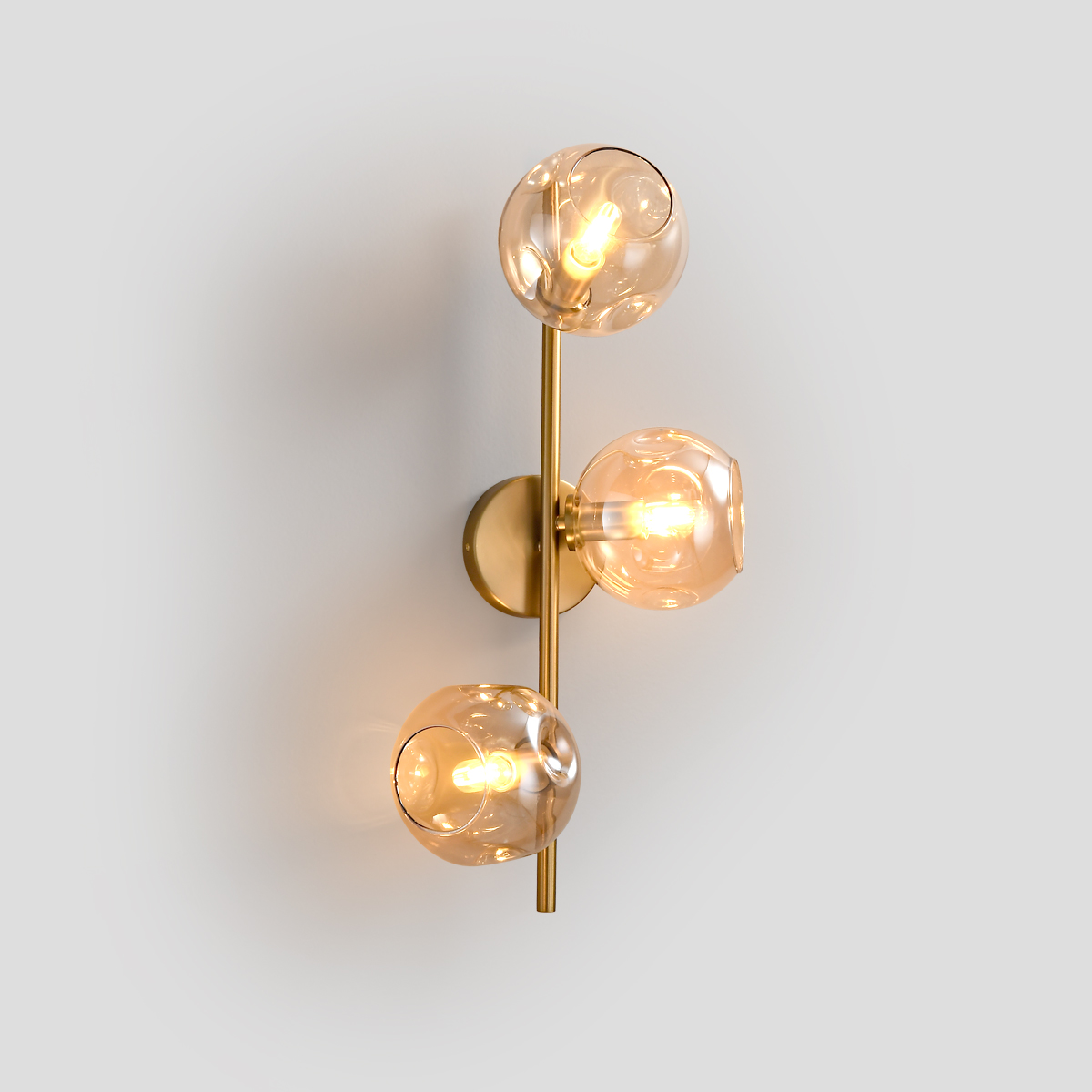 3-Light Modern Brass Wall Sconce 1 Front view of a 3-light modern brass wall sconce with amber glass globes.