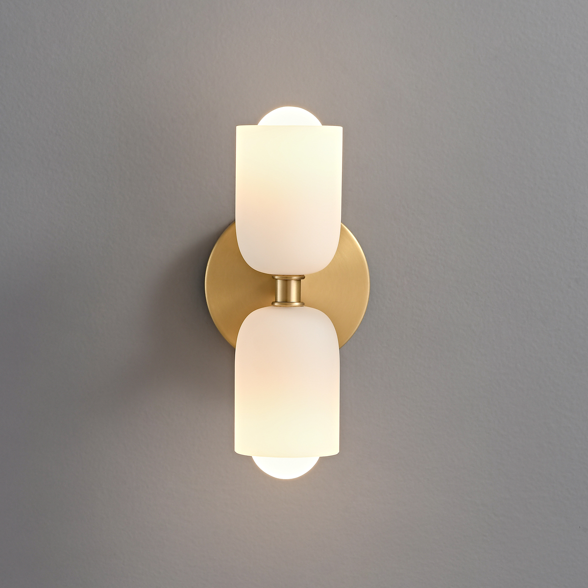 Mid-Century Modern Brass Wall Sconce 3 Mid-century modern brass wall sconce turned on, emitting a warm glow from both glass shades.